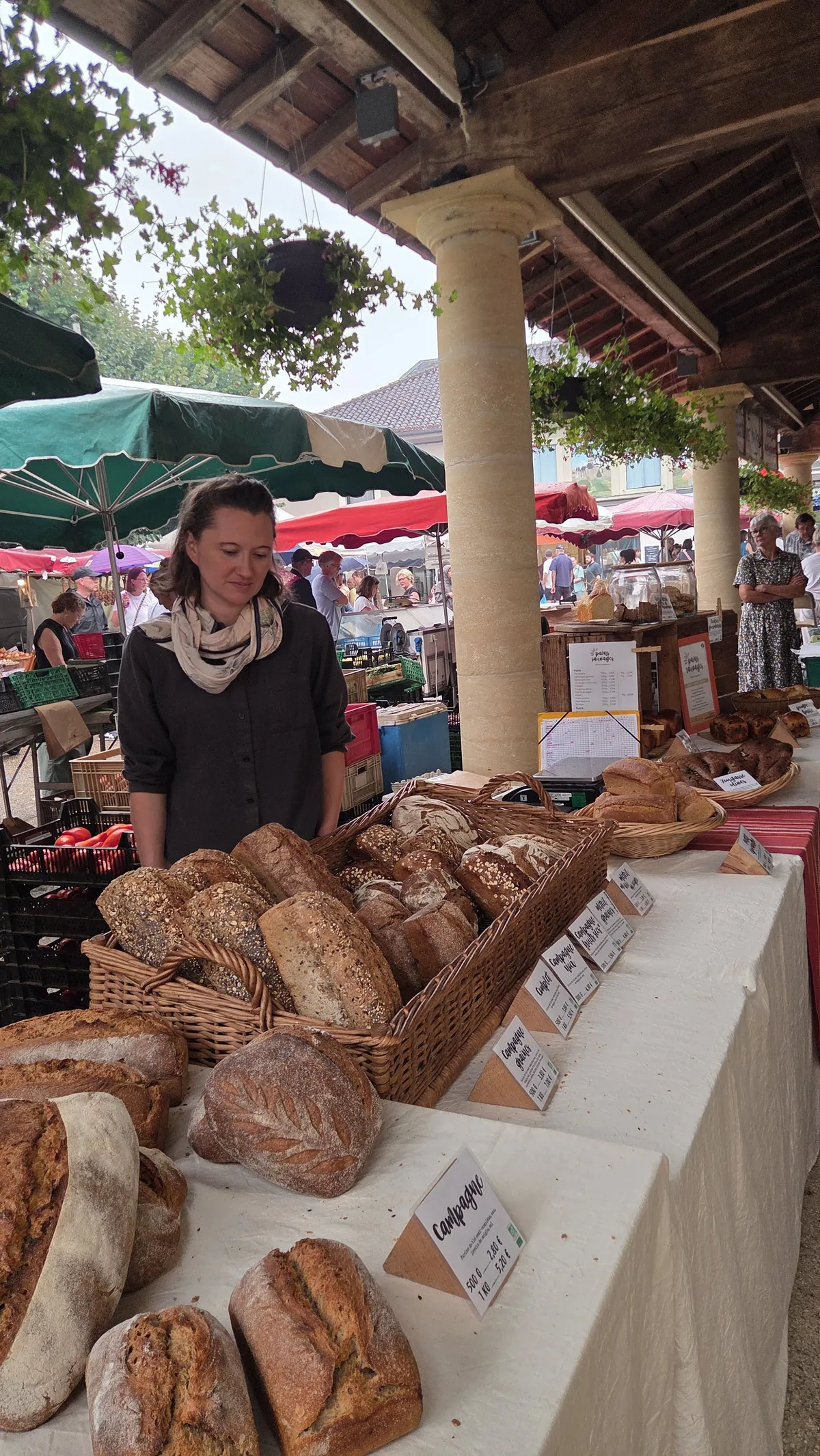 Tania derrière son étal de marché, les pains alignés dans les paniers et sur la table