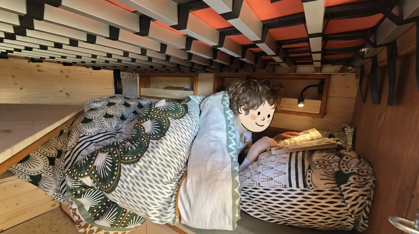 Enfant lisant dans sa couchette du van, éclairé par une liseuse