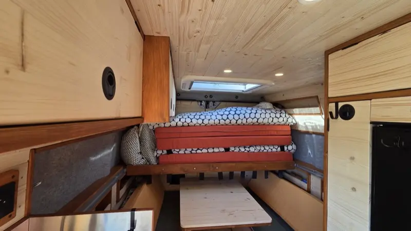 Séquence animée montrant la transformation du lit rétractable du van : de la position nuit (lit double déplié) à la position jour (espace de vie dégagé)