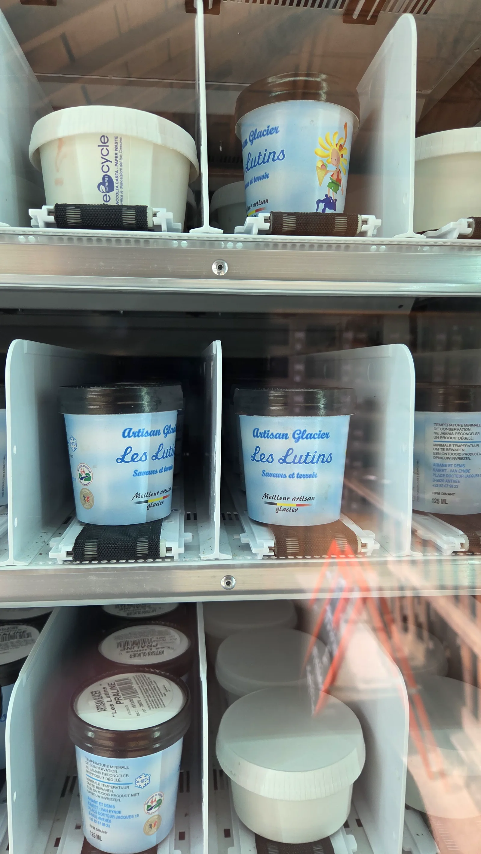 Intérieur d'un distributeur avec des pots de glace d'un artisan local aux côtés d'autres produits